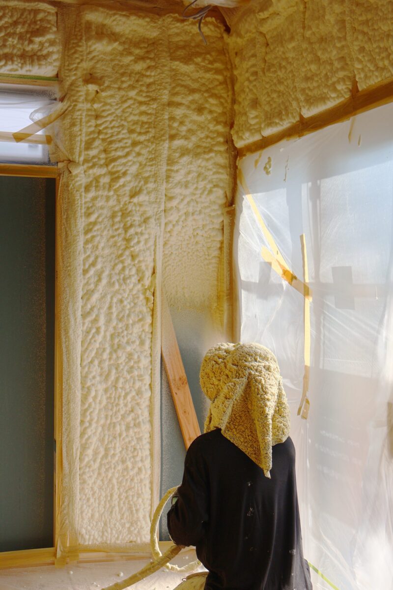 壁に断熱材と吹き付ける様子